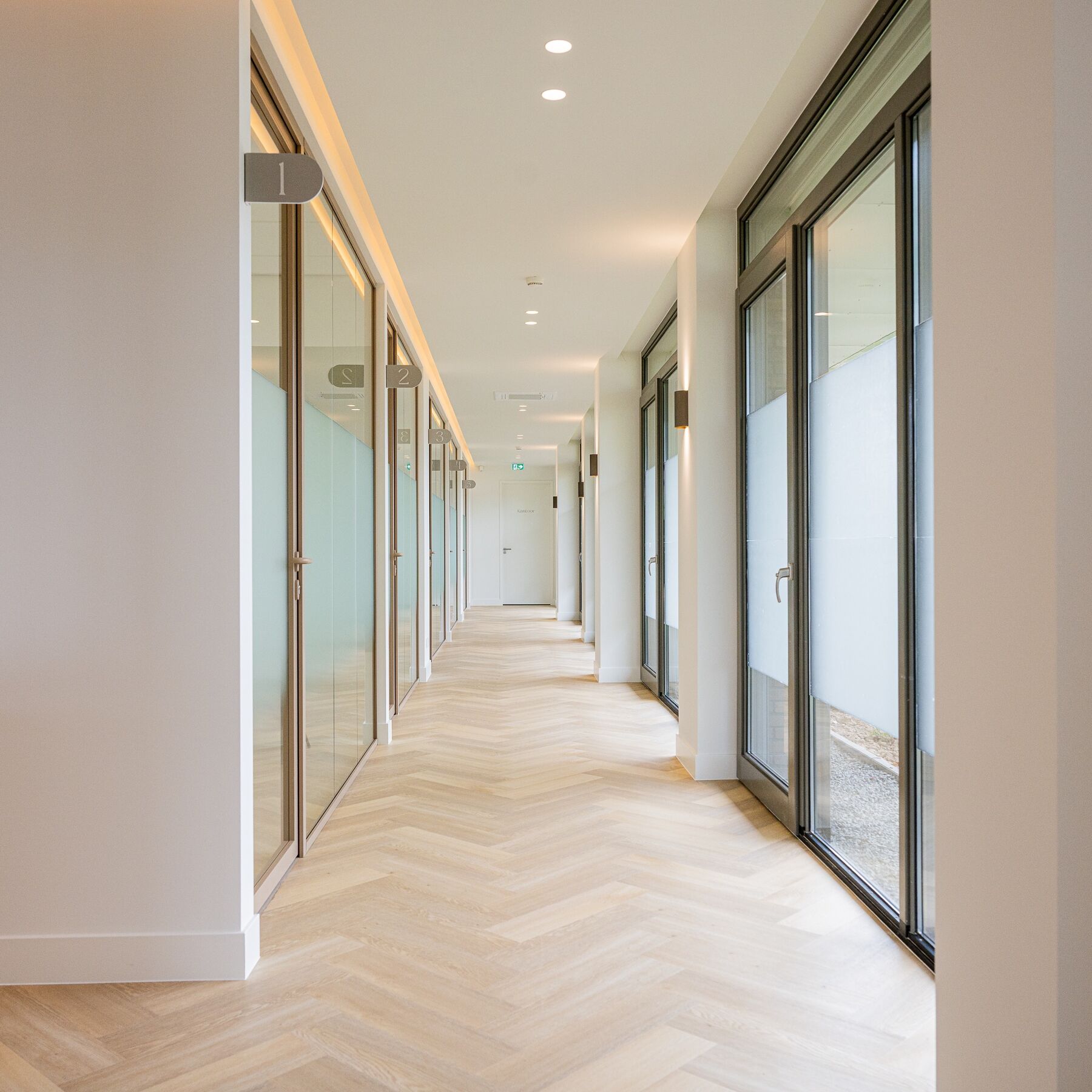 Gerealiseerde corridor met glazen behandelkamers